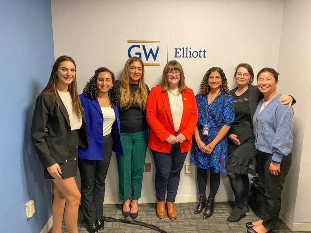 Group of people standing in front of GW Elliott sign