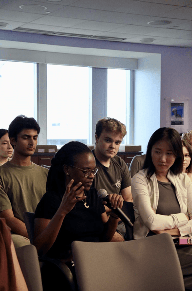 person with microphone in hand speaking amongst audience 
