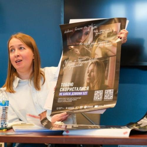 person holding up poster and speaking