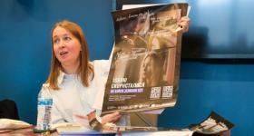 person holding up poster and speaking