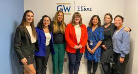 Group of people standing in front of GW Elliott sign